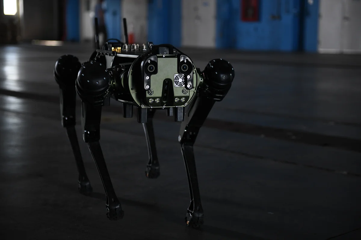 Photograph: U.S. Space Force / Senior Airman Samuel Becker Four-legged ground robot with cameras and sensors walking across the floor of an industrial hangar